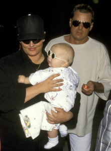 Wynonna Judd Wearing Black Clothing, Hat, Dark Sunglasses Walking And Holding Son Elijah With Now Ex Husband Arch Kelley Wearing Cream Colored Clothing