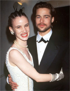 Juliette Lewis Wearing Jewel Earrings, Long Strand Of Pearls, White Gloves And White Sleeveless Gown With Her Arms Around Brad Pitt Wearing Black Tux, White Shirt And Cross Tie