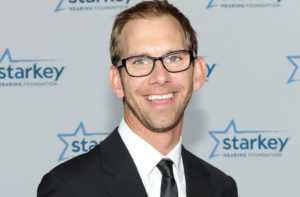 Smiling Michael Kutcher, Twin Brother of Ashton Kutcher, Wearing Black Suit and Tie With White Shirt